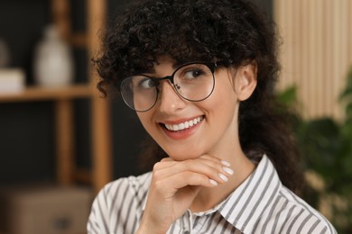 Photo of Portrait of beautiful woman with curly hair indoors. Attractive lady smiling and posing for camera