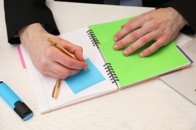 Photo of Man taking notes at white wooden table, closeup