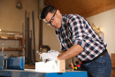 Professional carpenter working with wooden plank in workshop