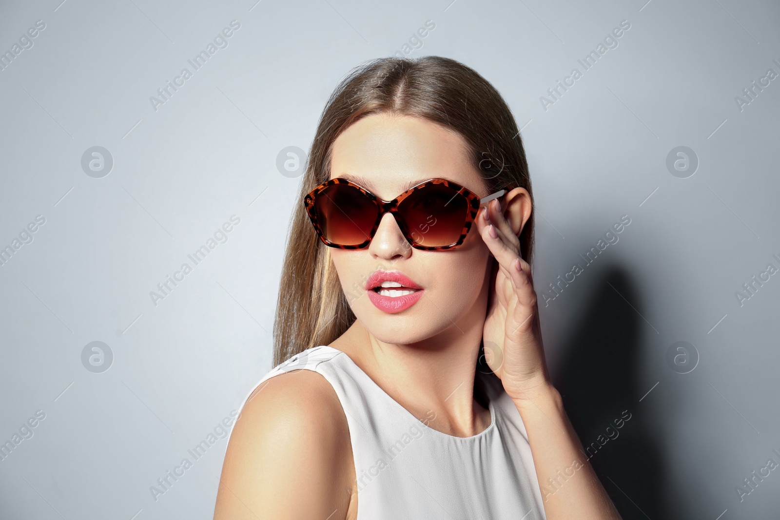 Photo of Young woman wearing stylish sunglasses on light grey background