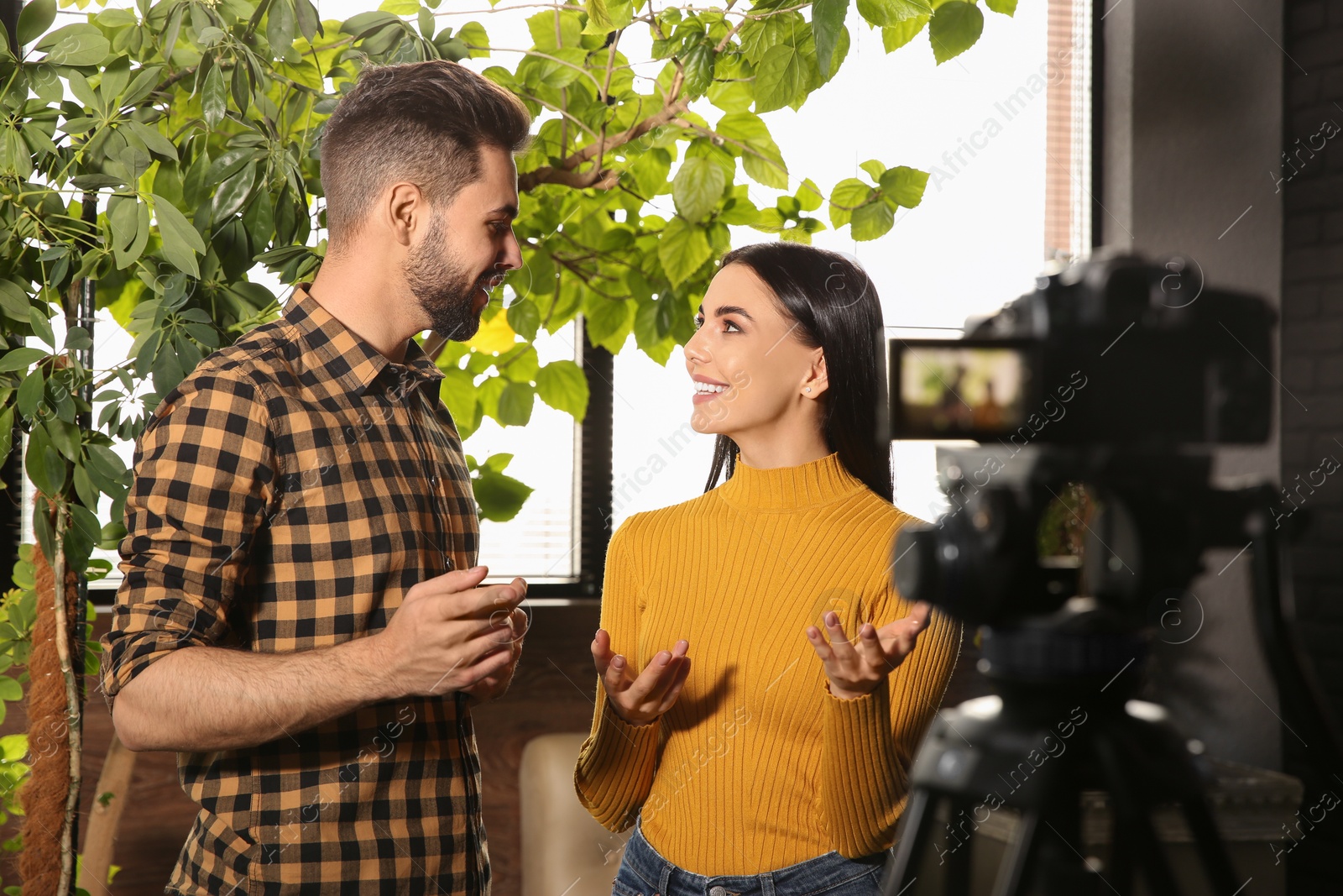 Photo of Young bloggers recording video on camera indoors