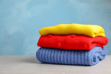 Photo of Stack of folded knitted sweaters on table. Space for text