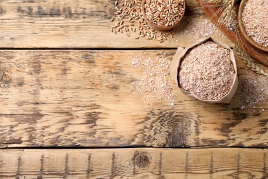 Photo of Wheat bran on wooden table, flat lay. Space for text