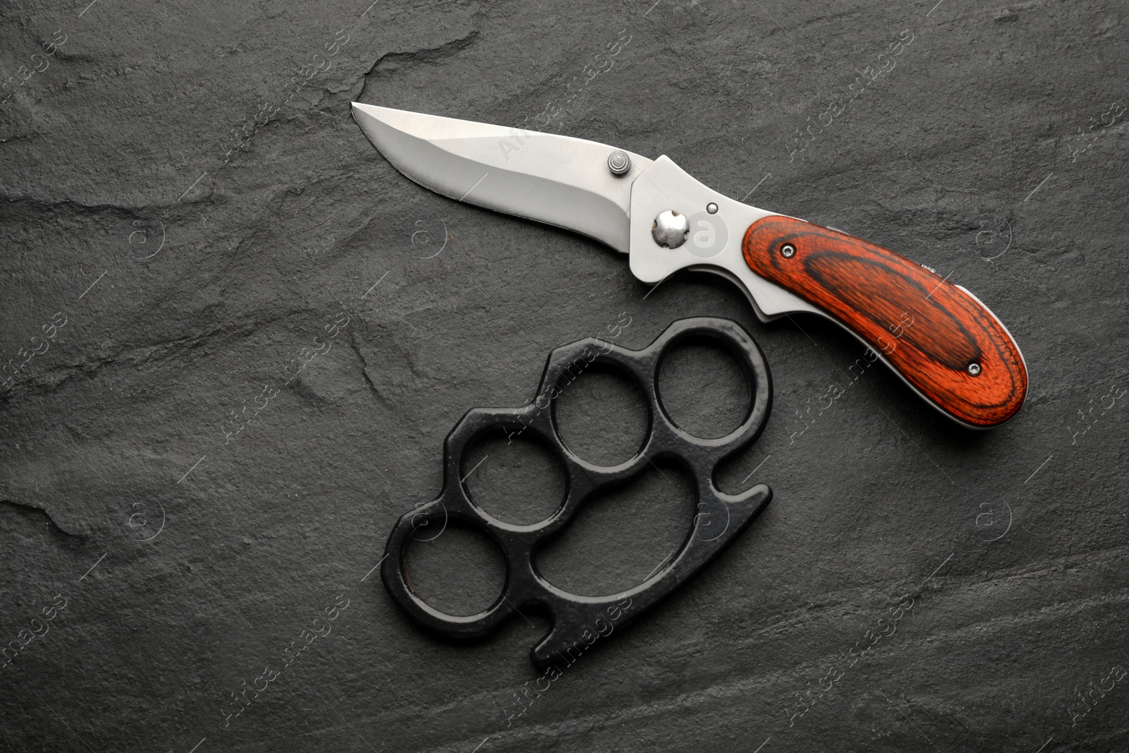 Photo of Brass knuckles and knife on black background, flat lay