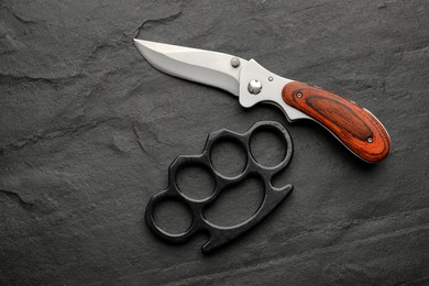 Photo of Brass knuckles and knife on black background, flat lay