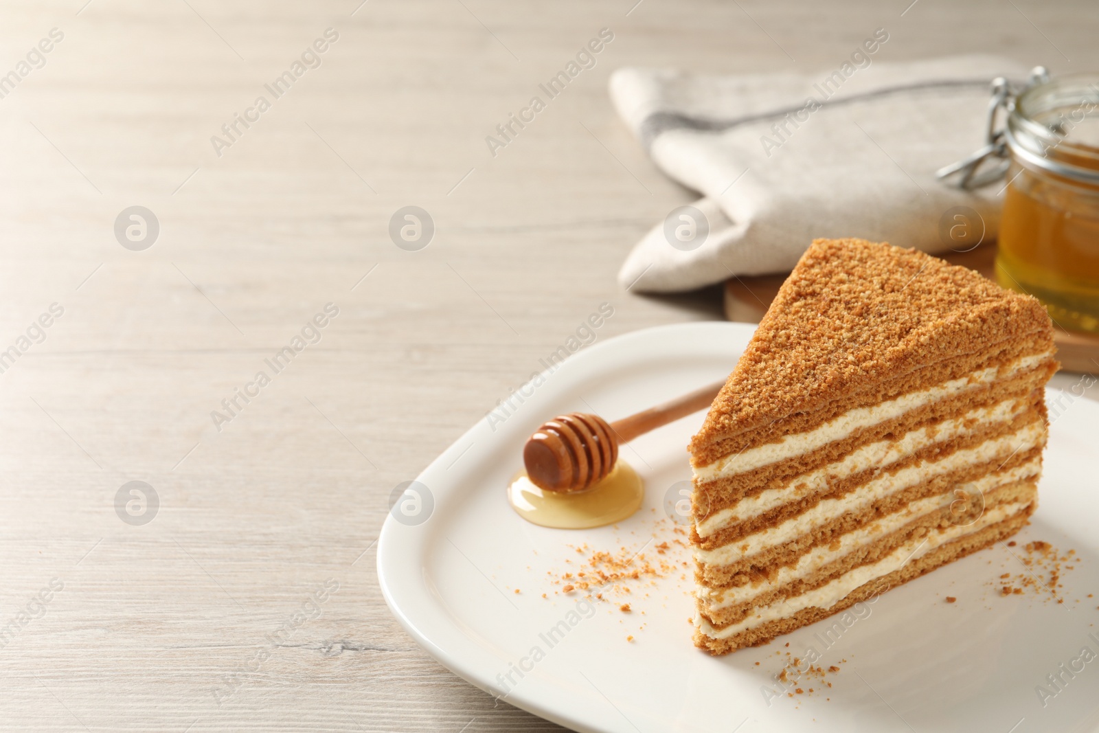 Photo of Slice of delicious layered honey cake served on wooden table. Space for text