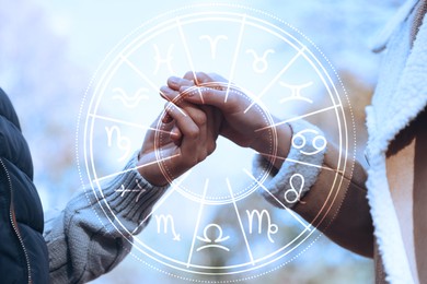 Image of Horoscope compatibility. Loving couple holding hands outdoors and zodiac wheel