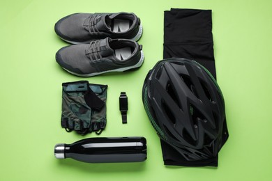 Photo of Flat lay composition with different cycling accessories and clothes on green background