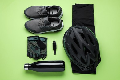 Flat lay composition with different cycling accessories and clothes on green background