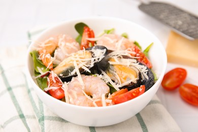 Photo of Bowl of delicious salad with seafood on white tiled table, closeup