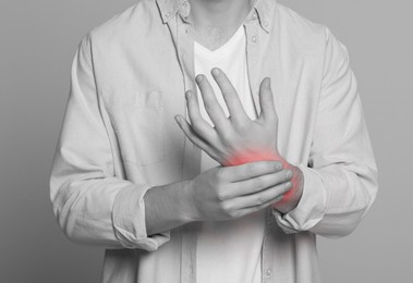 Man suffering from pain in wrist, closeup. Black and white effect