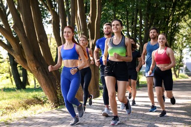 Group of people running in park on sunny day