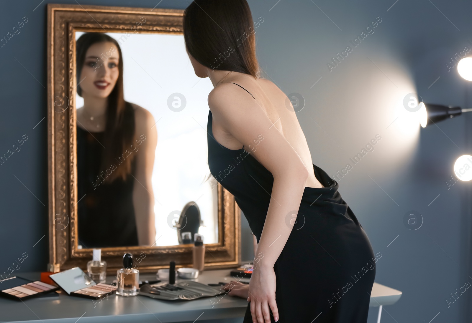 Photo of Portrait of beautiful woman with bright makeup near mirror indoors