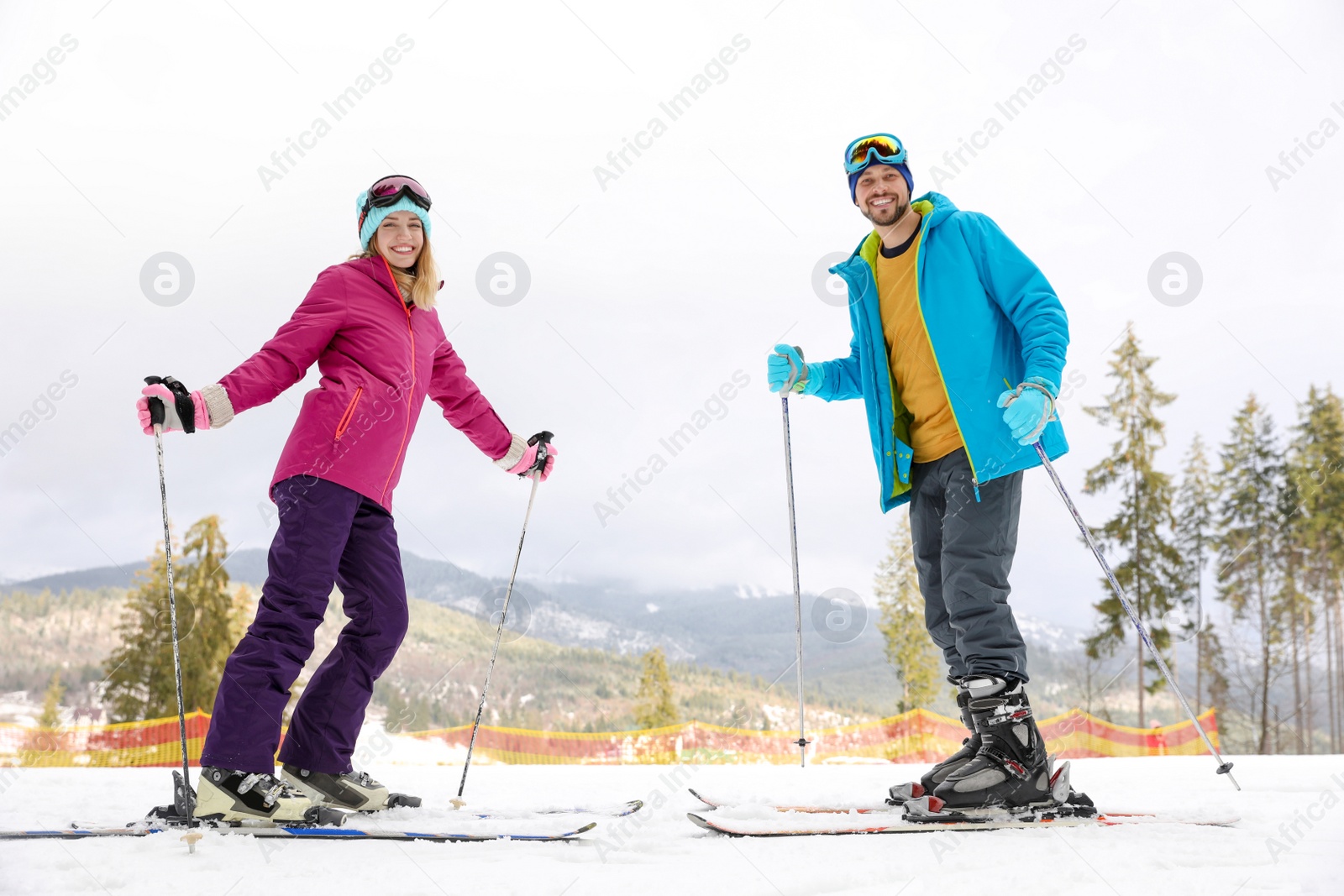 Photo of Couple of skiers on slope at resort. Winter vacation