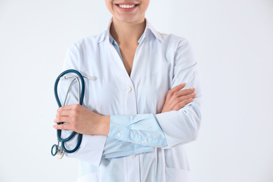 Young doctor with stethoscope on white background, closeup