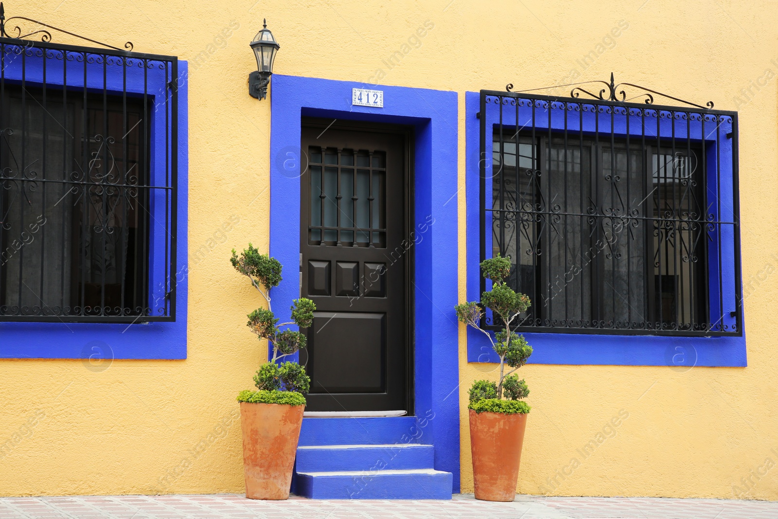 Photo of Entrance of residential house with door, potted plants and windows