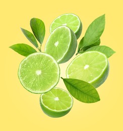 Image of Fresh lime fruits and green leaves falling on yellow background