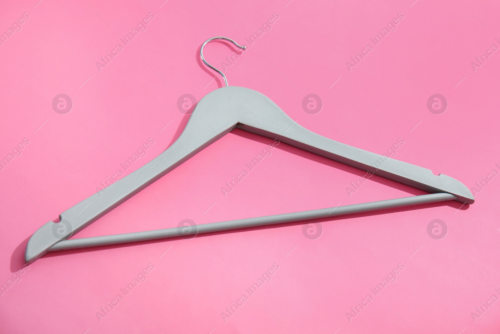 Photo of Empty wooden clothes hanger on color background