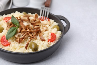 Photo of Tasty couscous with mushrooms, olives and tomatoes on grey table, closeup. Space for text