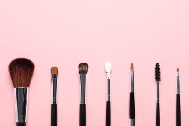 Photo of Different makeup brushes on pink background, flat lay. Space for text