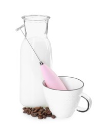 Photo of Pink mini mixer (milk frother), cup, coffee beans and bottle isolated on white