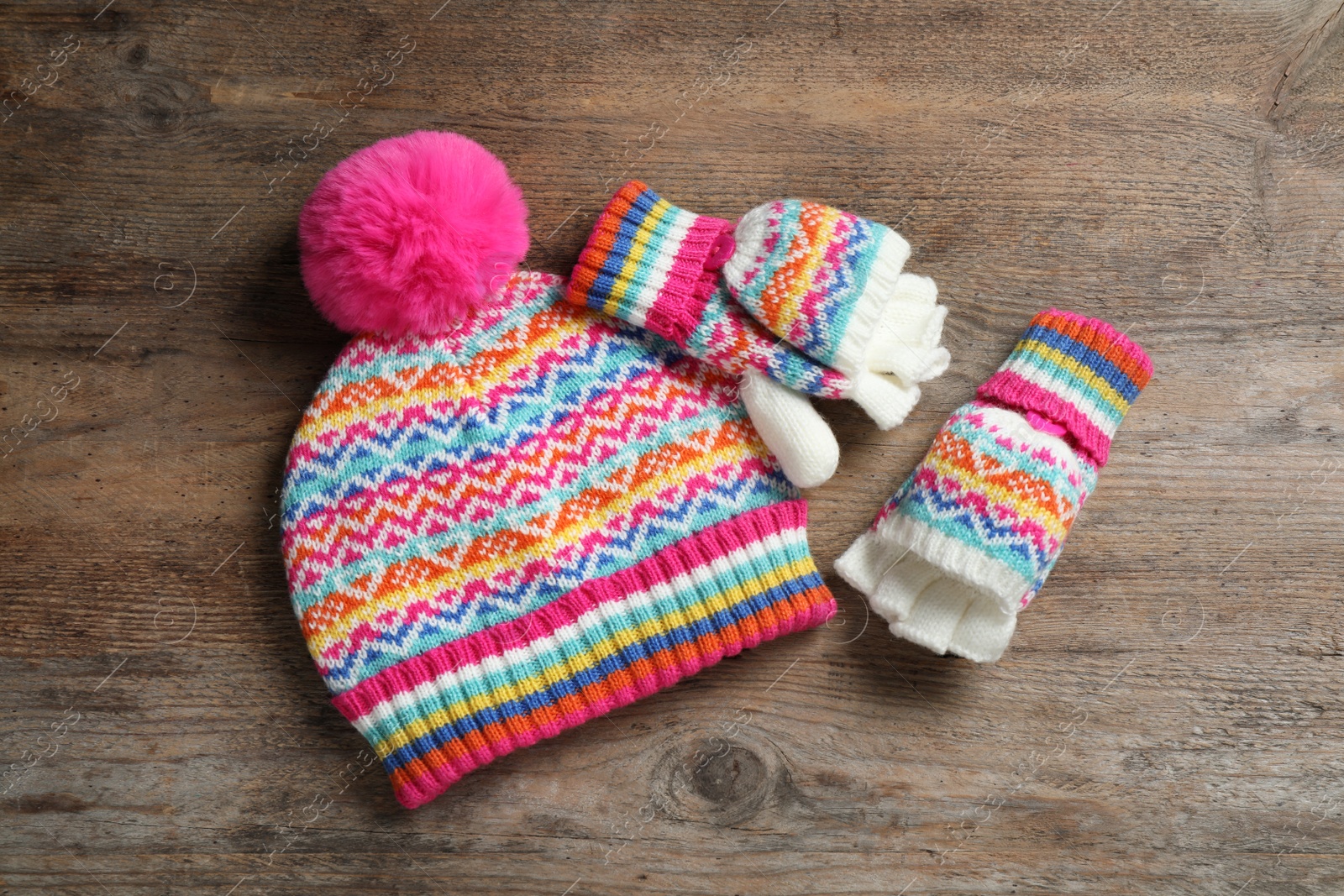 Photo of Warm knitted hat and mittens on wooden background, flat lay