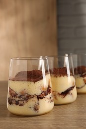 Photo of Delicious tiramisu in glasses on wooden table