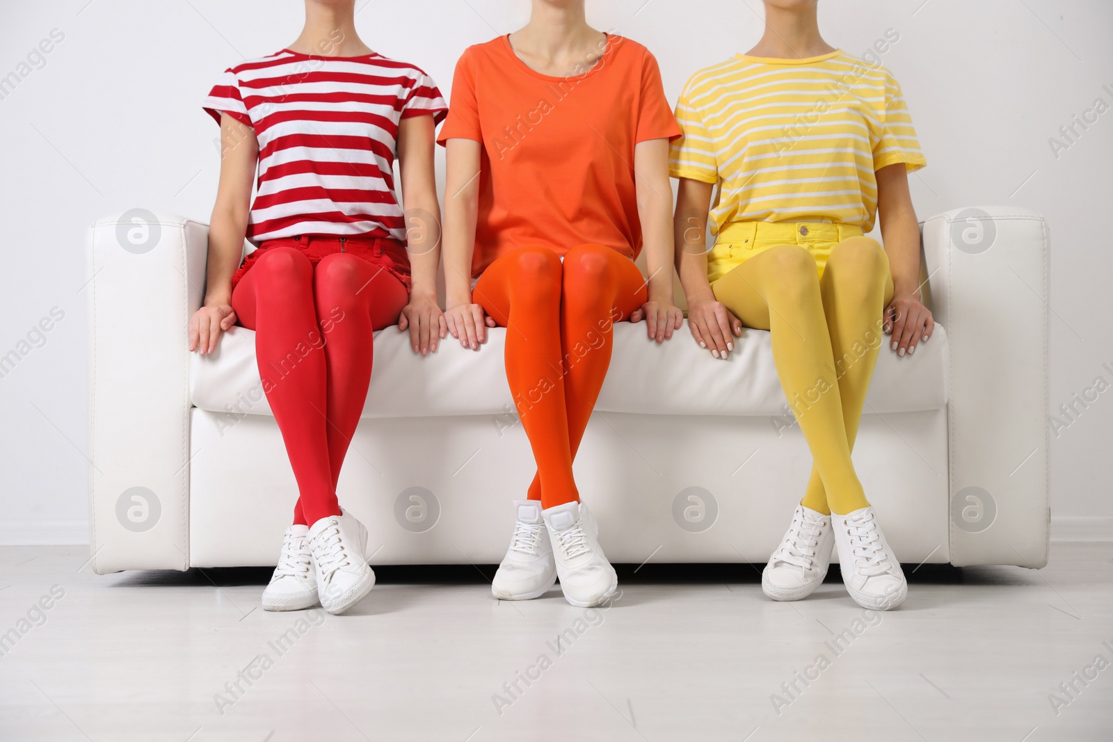 Photo of Women wearing bright tights sitting on sofa indoors, closeup