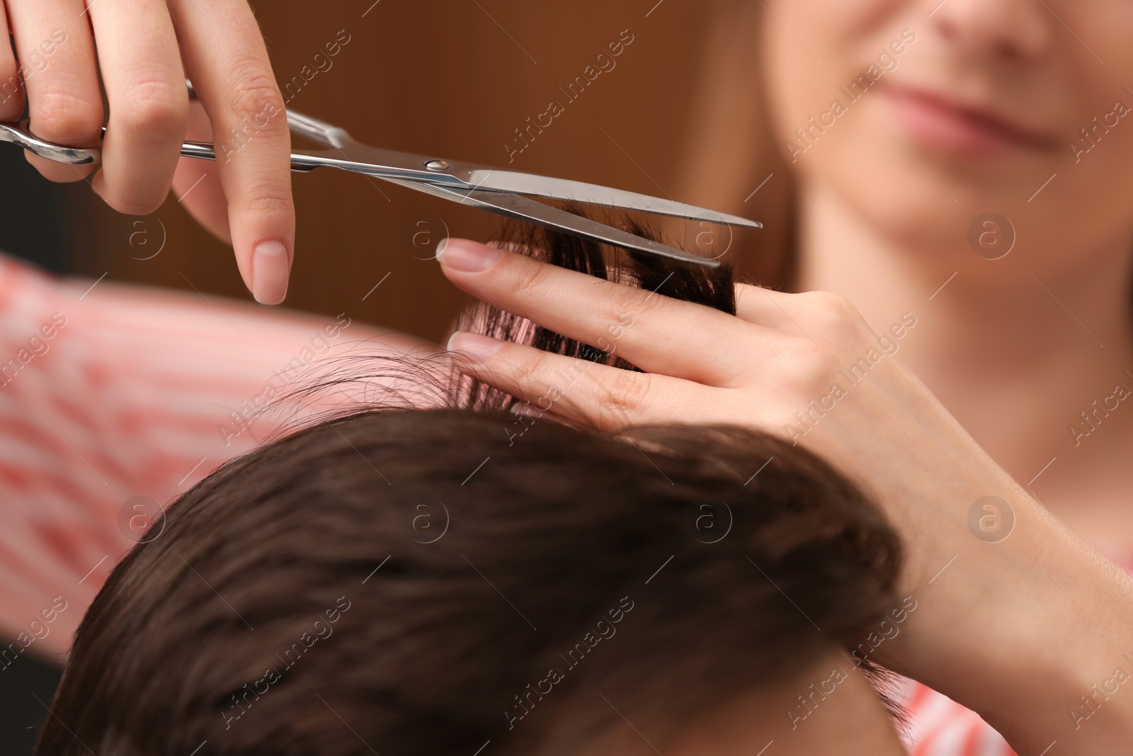 Photo of Barber making stylish haircut with professional scissors in beauty salon, closeup