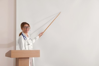 Photo of Doctor giving lecture near projection screen in conference room, space for text