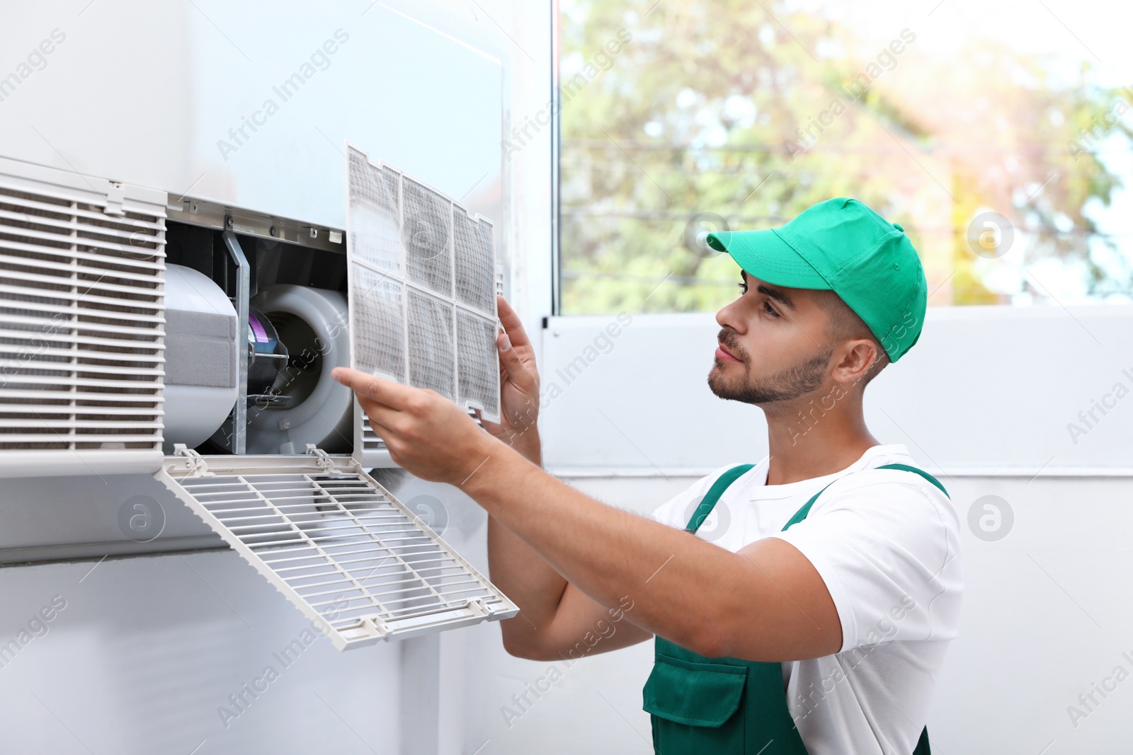 Photo of Professional technician maintaining modern air conditioner indoors