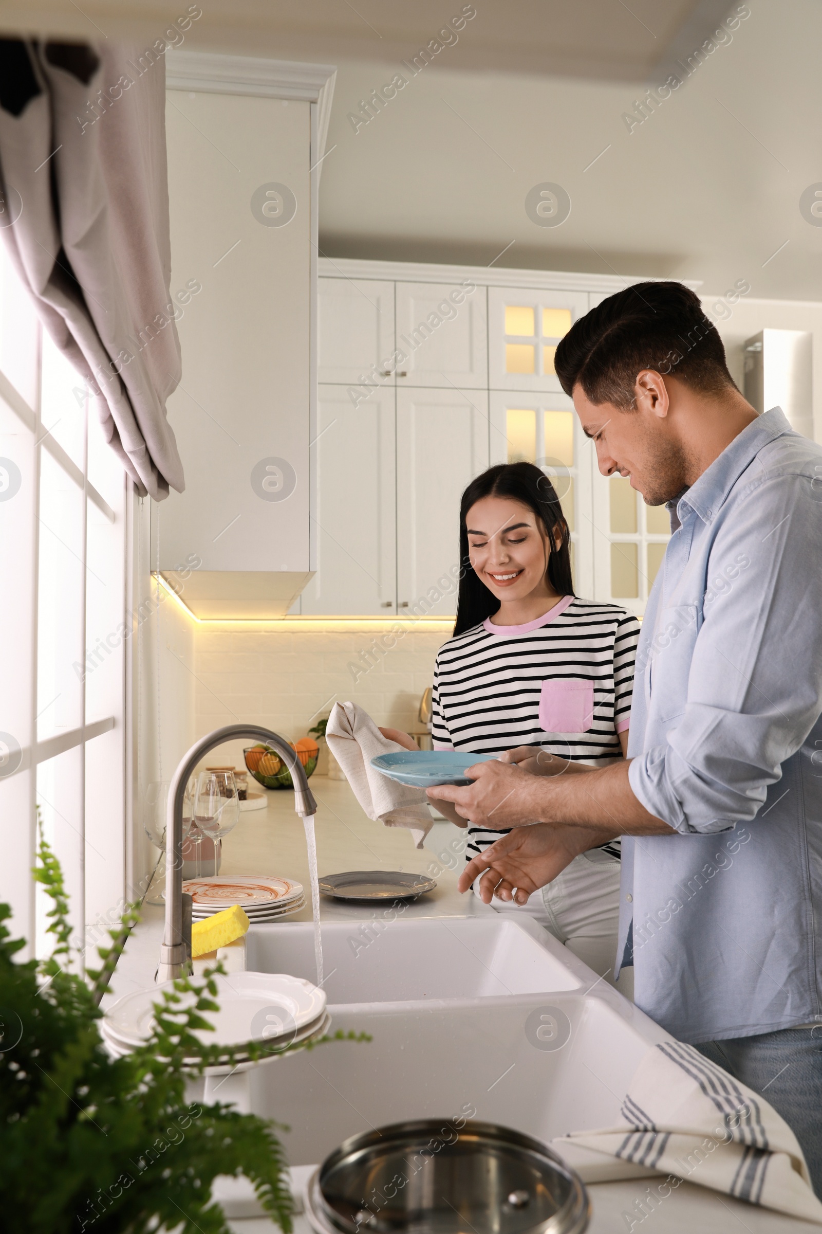 Photo of Happy lovely couple washing dishes in kitchen