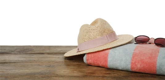 Beach towel, straw hat and sunglasses on wooden surface against white background. Space for text