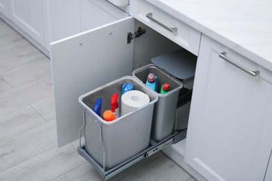 Open cabinet with different cleaning supplies in kitchen