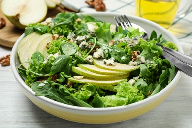 Photo of Fresh salad with pear on white wooden table, closeup