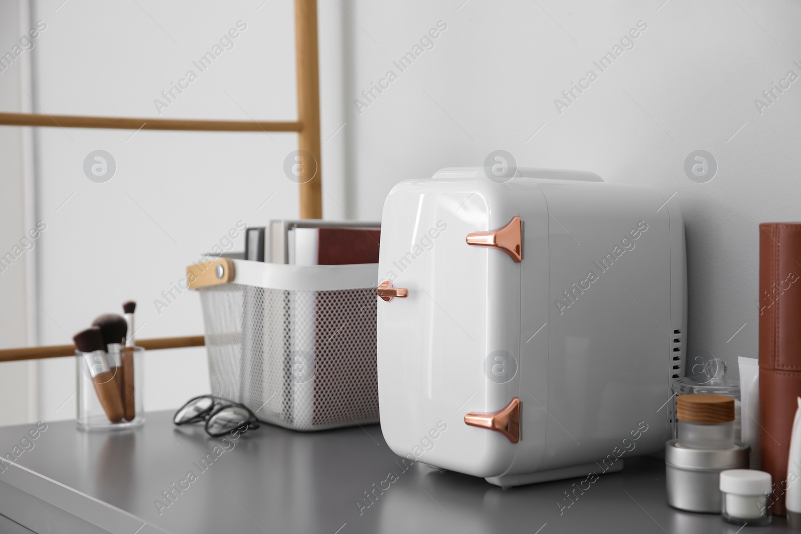 Photo of Cosmetics refrigerator and skin care products on grey vanity table indoors