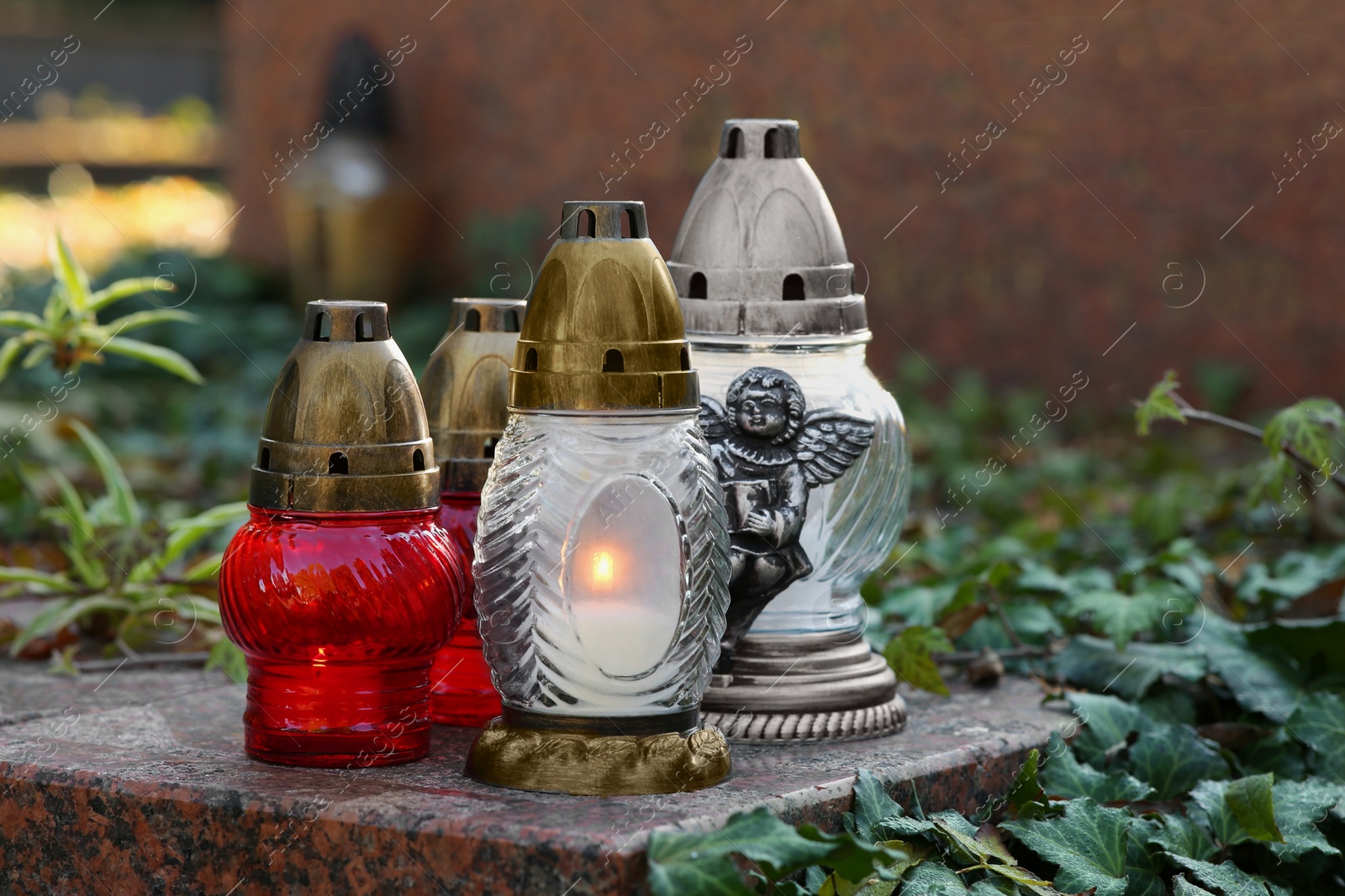 Photo of Grave lanterns and ivy near tombstone in cemetery