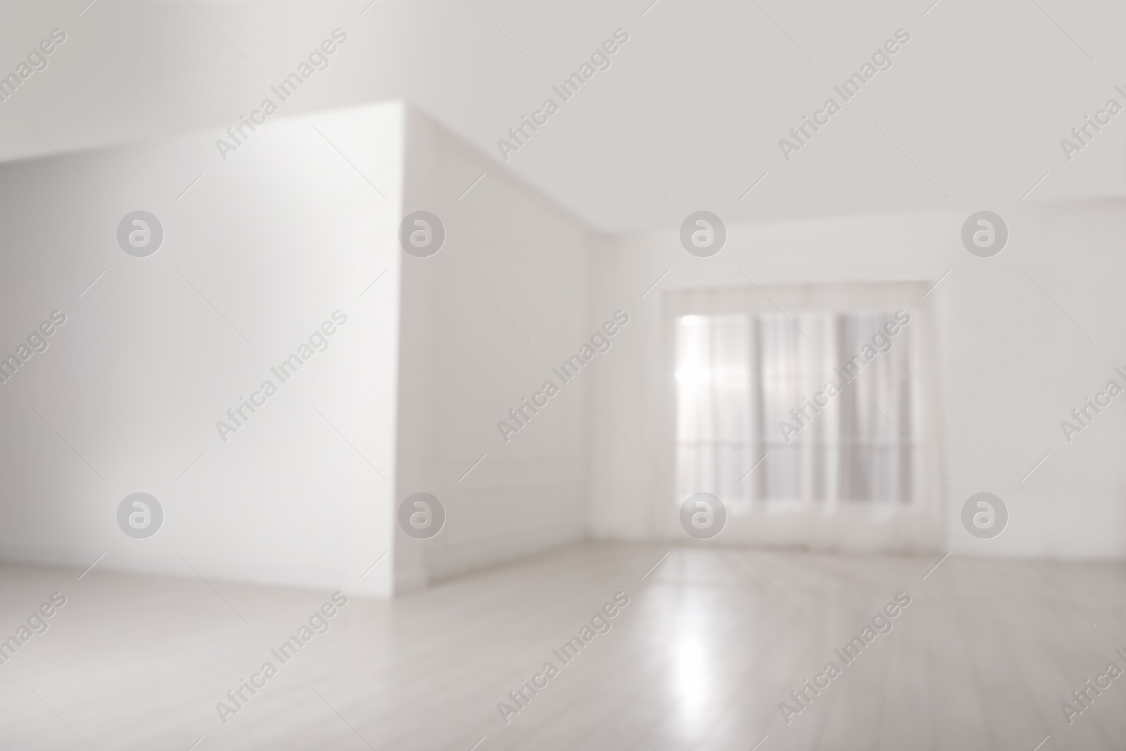 Photo of Empty room with white walls and large window, blurred view