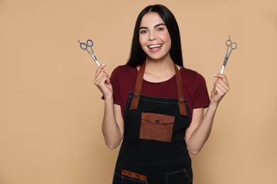 Photo of Portrait of happy hairdresser with professional scissors on beige background