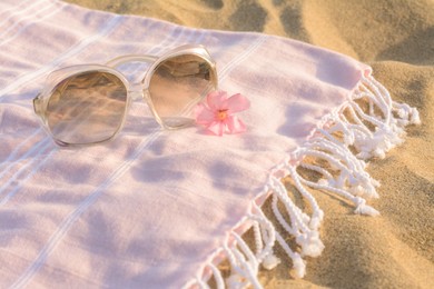 Photo of Beautiful sunglasses with tropical flower on pink blanket