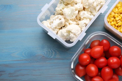 Photo of Plastic and glass containers with fresh products on light blue wooden table, flat lay. Space for text