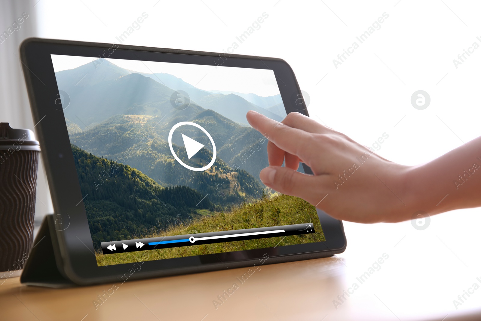 Image of Woman watching video on tablet at wooden desk, closeup