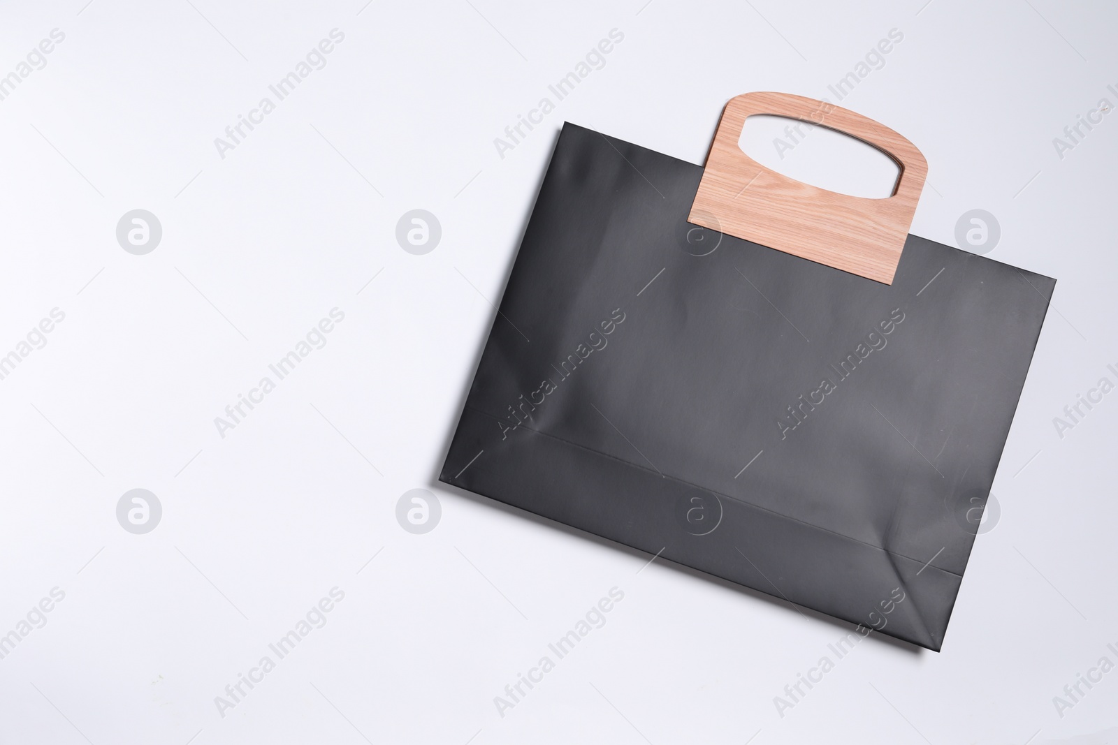 Photo of One black paper shopping bag on white background, top view. Space for text