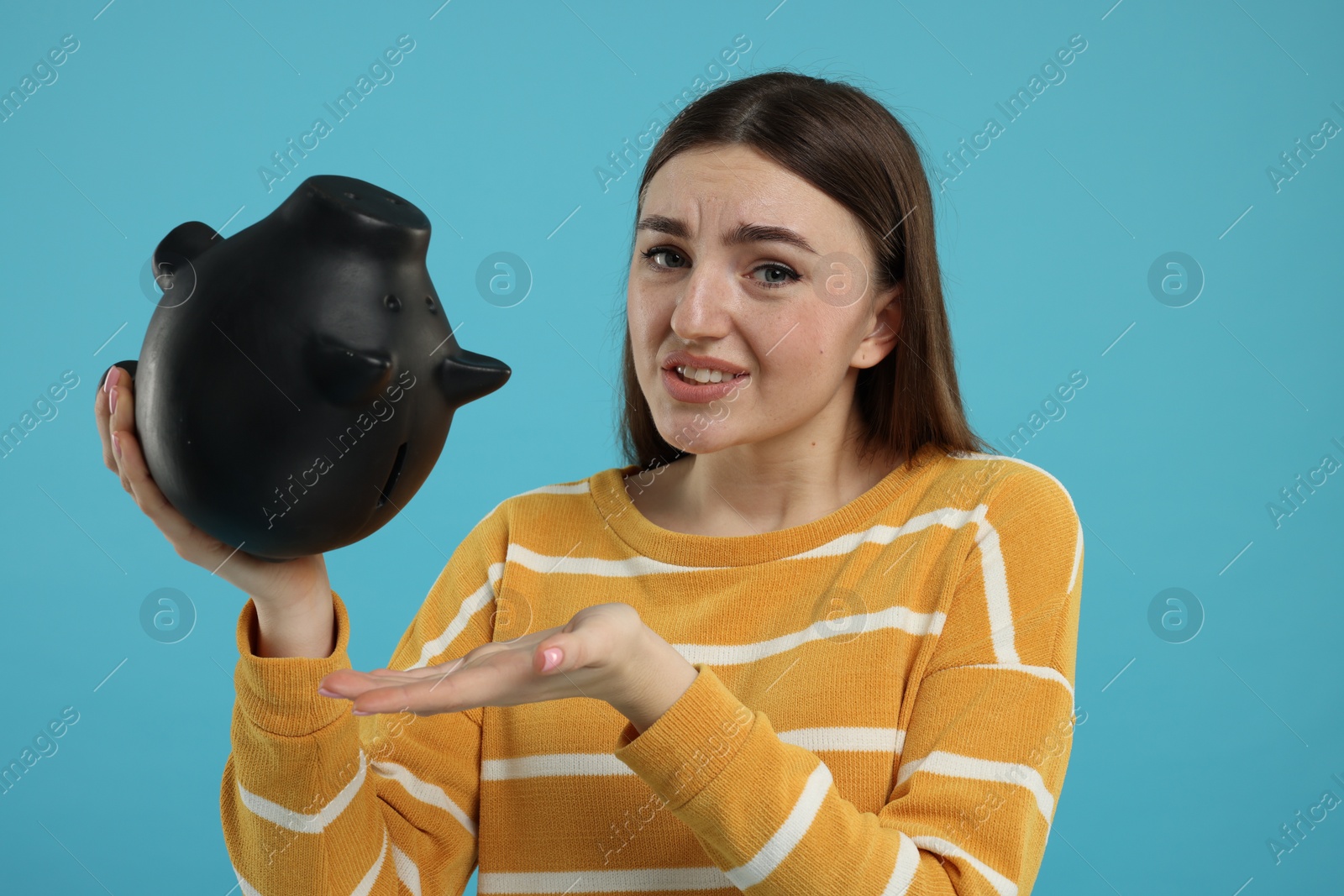 Photo of Sad woman with piggy bank on light blue background