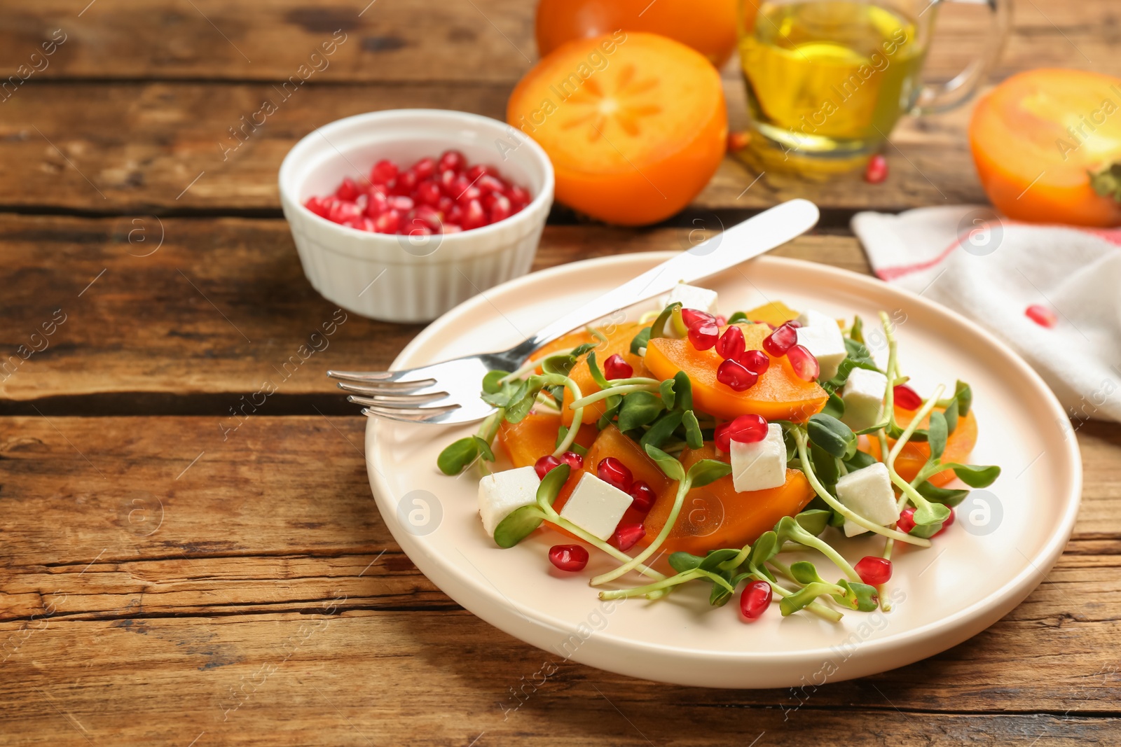 Photo of Delicious persimmon salad served on wooden table, closeup