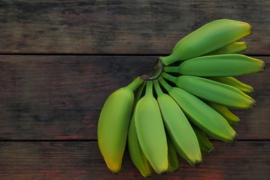 Photo of Bunch of delicious bananas on wooden table, top view. Space for text