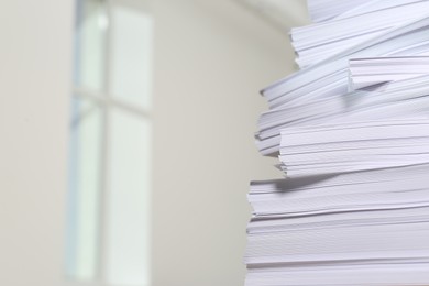 Photo of Stack of paper sheets against blurred background, closeup. Space for text