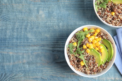 Photo of Healthy quinoa salad with vegetables in bowls on wooden table, top view. Space for text