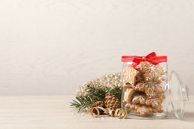 Tasty Christmas cookies in glass jar and festive decor on beige wooden table, space for text