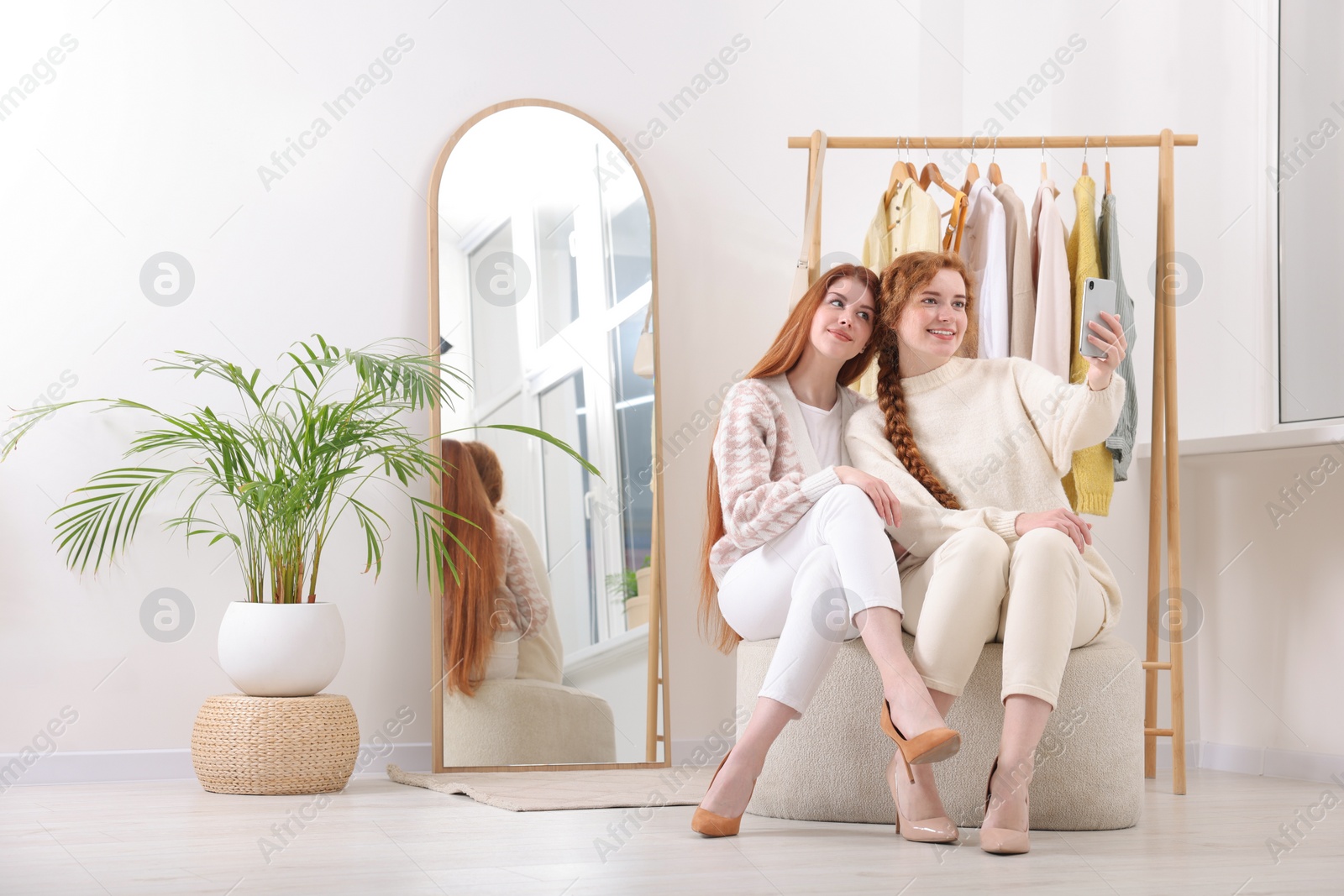 Photo of Beautiful young sisters taking selfie in dressing room